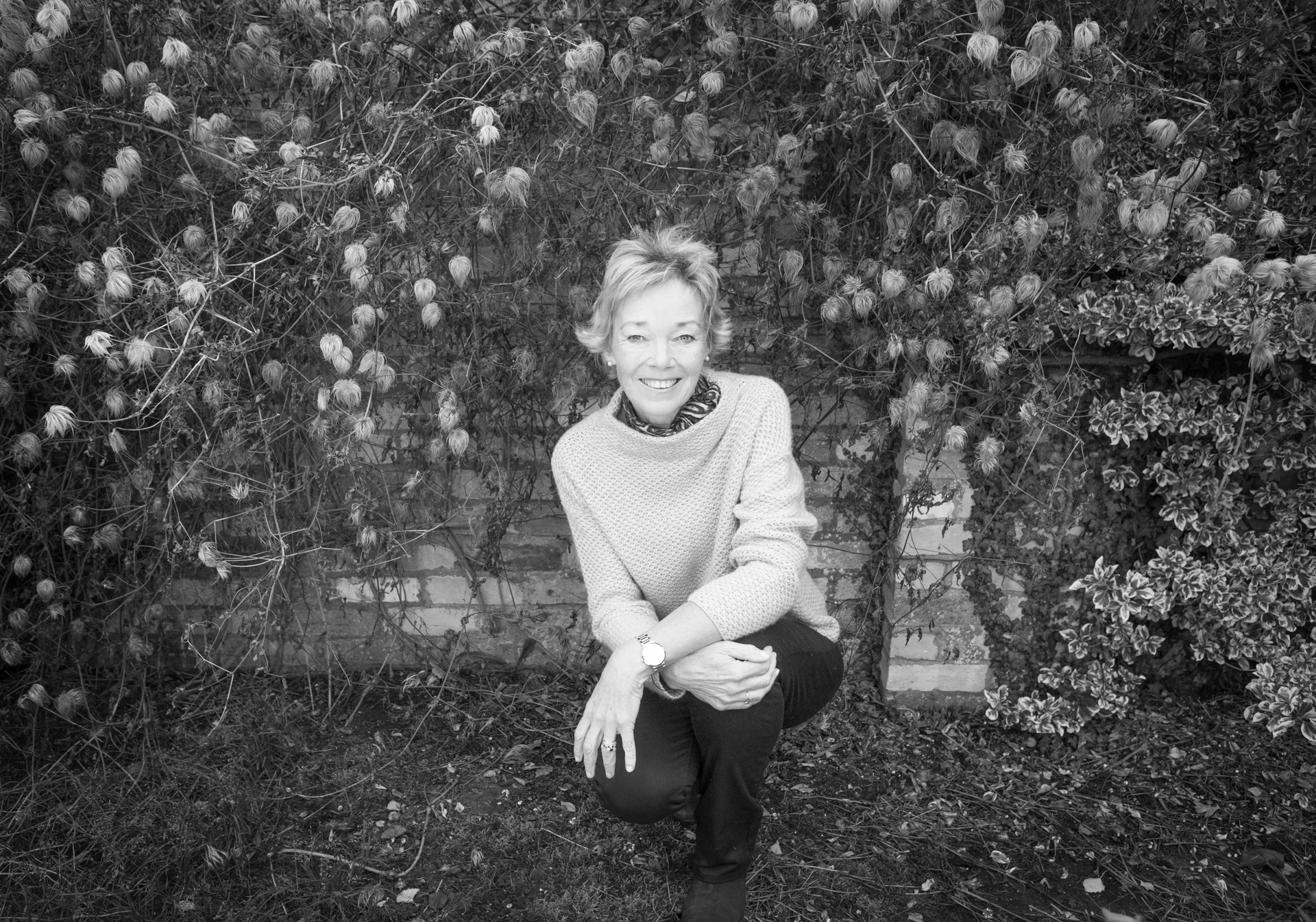 Black and white portrait of a woman laughing naturally outdoors, captured without posing or retouching.