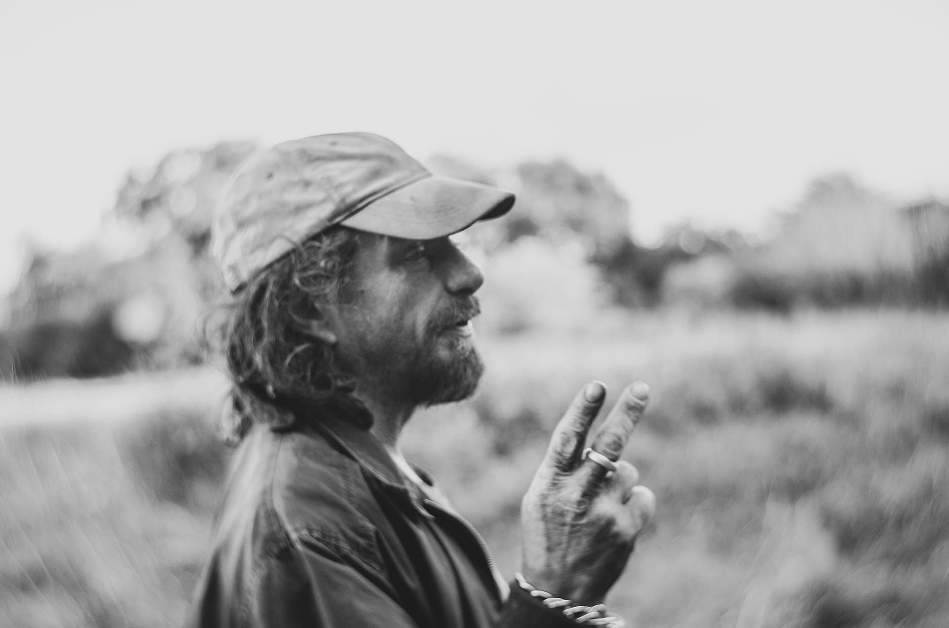 Man walking outdoors, photographed handheld with motion blur, cigarette raised mid-gesture