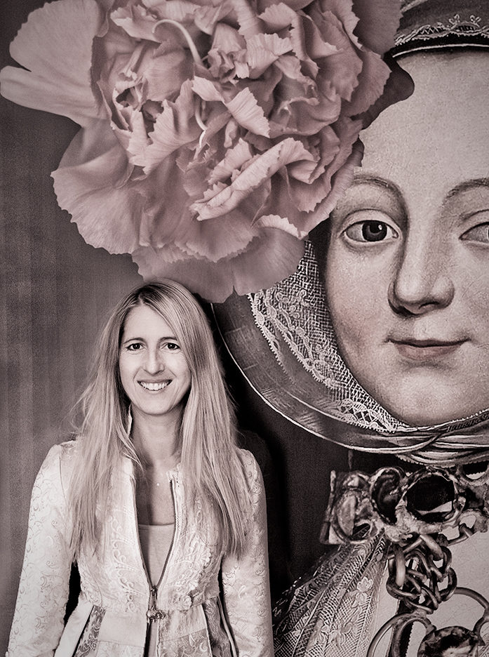Portrait of photographer Tamara Peel standing beside a historic painted female portrait