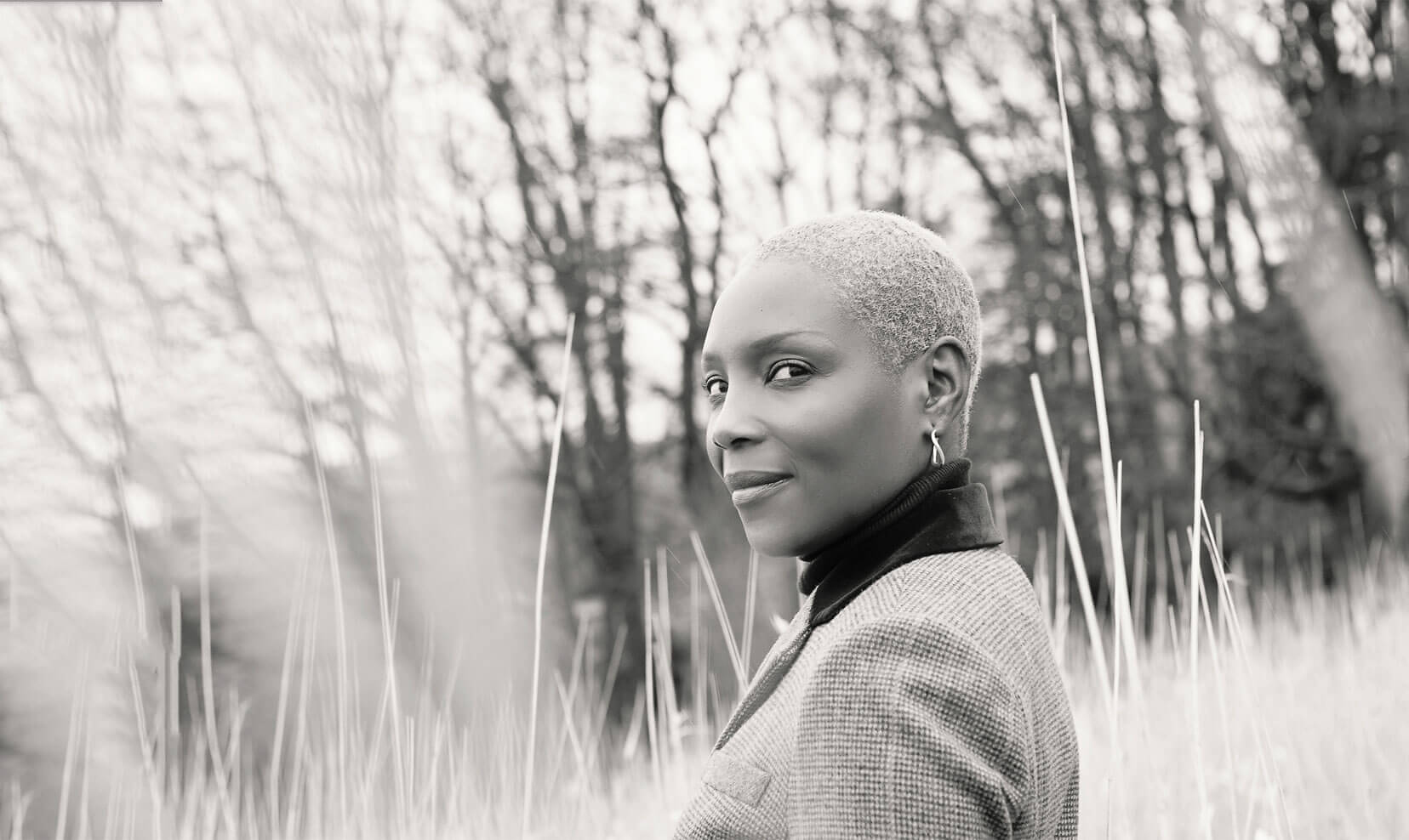 Portrait of a woman standing in tall grass, looking directly towards the camera