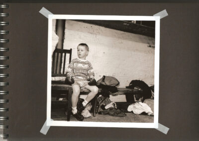 Young boy in a boxing gym looks away from the camera, lost in thought.