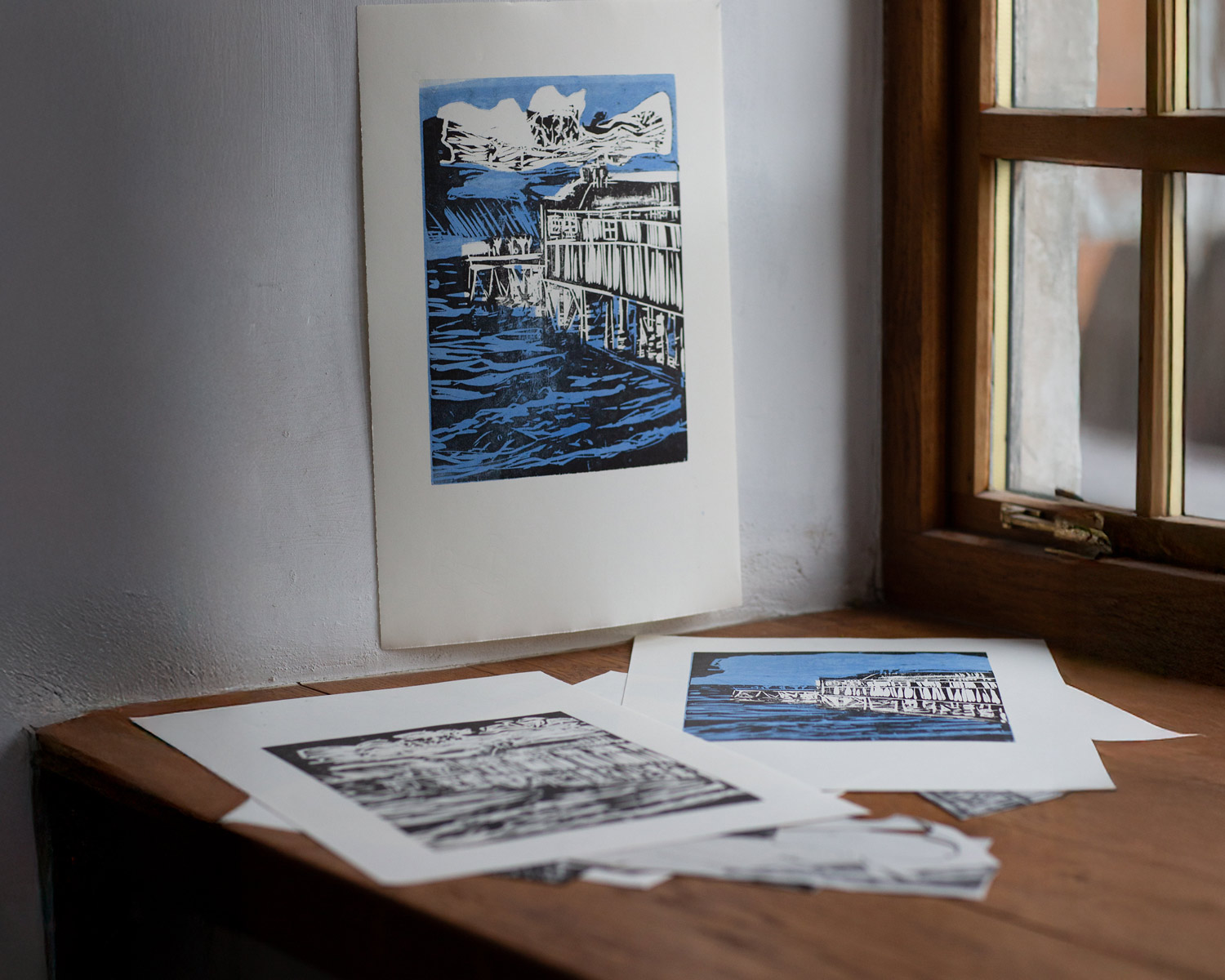 First lino print made using two plates, shown resting on a wooden table beside a window.