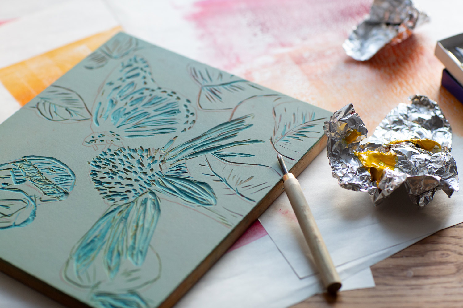 Lino suicide plate partway through the printmaking process, showing layered carving and coloured ink.